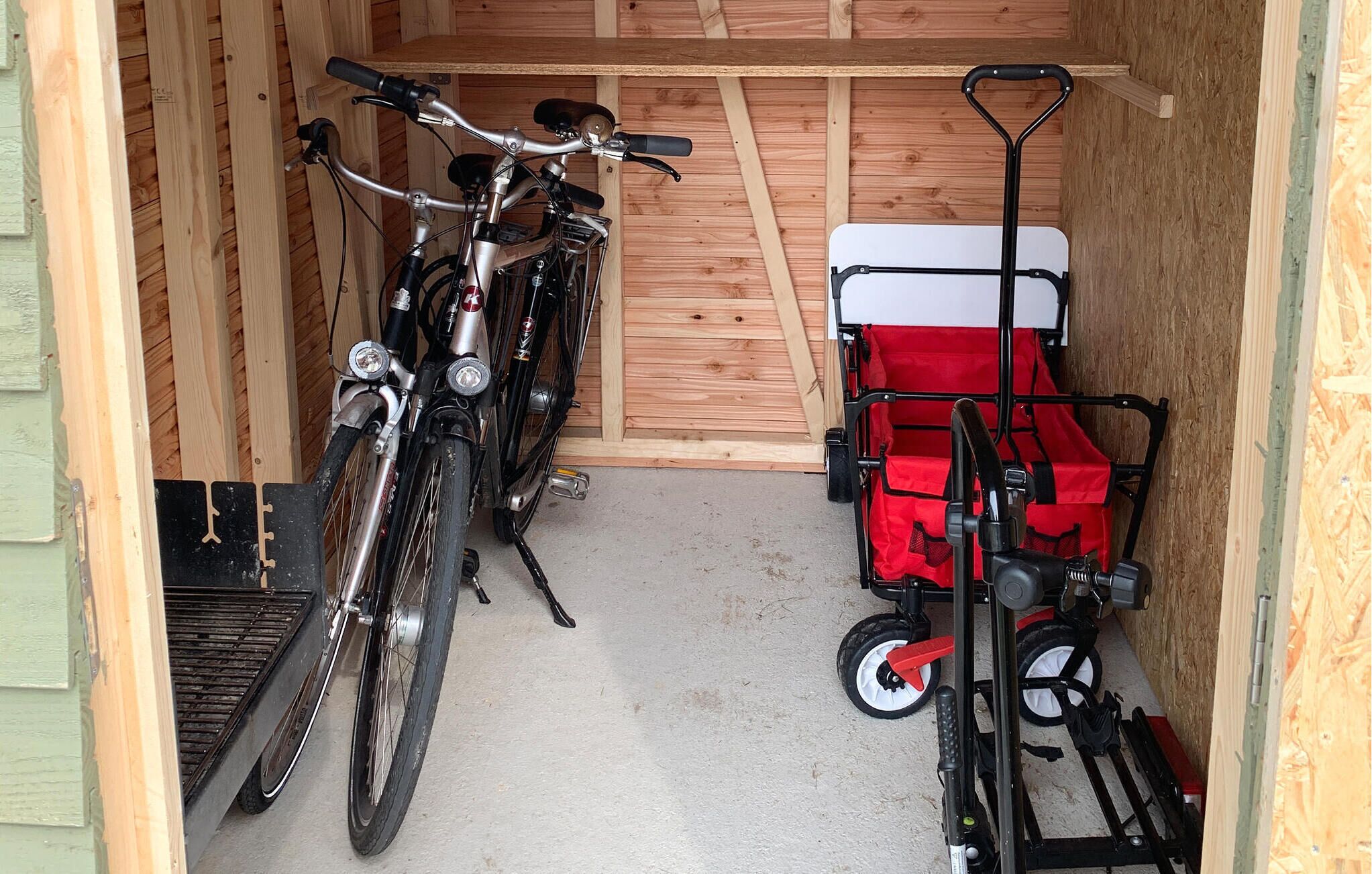 En garage med to cykler og en rød transportvogn.