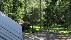 A forested area with a gravel path, a picnic table, and a white building. - Cozy Mazama Studio on 5 Acres-Trail Access & Views (Mazama)