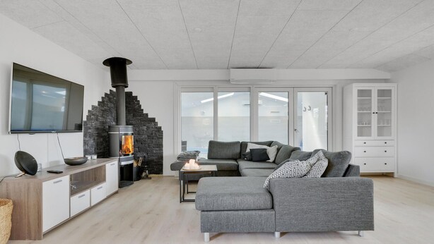 Ein modernes Wohnzimmer mit Kamin aus Stein, grauem Sofa und einem weißen Schrank.