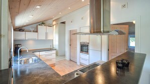 Uma cozinha moderna com ilha central, eletrodomésticos de aço inoxidável e vigas de madeira no teto.