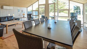 Um quarto amplo com uma grande mesa de jantar rodeada por cadeiras, um sofá e uma televisão.