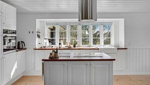 A kitchen with white cabinetry, a wooden countertop, a large window with multiple panes, and a stainless steel range hood. - 3 bedroom gorgeous home in Glesborg (Glesborg)