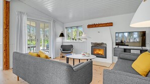 A modern living room with grey sofas, a round coffee table, a fireplace, and a TV. - 3 bedroom gorgeous home in Glesborg (Glesborg)