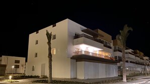 Un immeuble moderne à plusieurs étages, doté de balcons et d’une entrée bien éclairée.