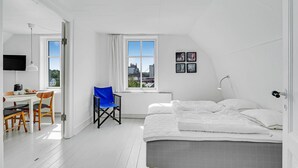 A bedroom with a bed, a desk, a chair, and a window with a city view.