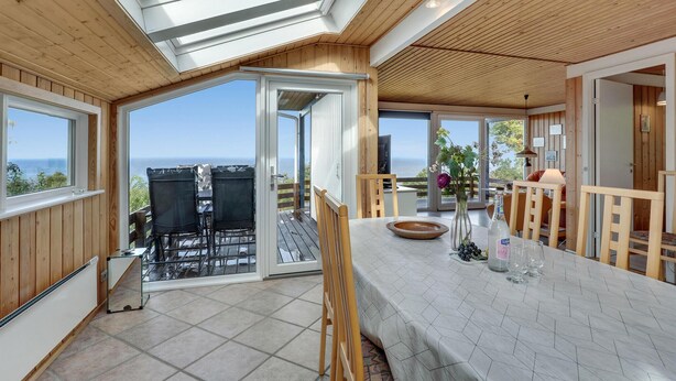 A spacious room with a large sliding glass door leading to an outdoor area, a wooden ceiling, and a view of the sea. - Stunning home in Hasle with WiFi (Hasle)