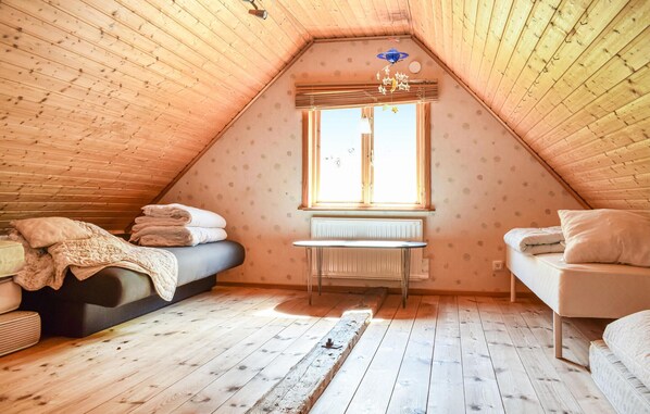 Un dormitorio acogedor en el ático con techo inclinado, una ventana con persianas, un radiador y una cama con almohadas.