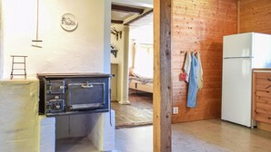 A kitchen with a vintage stove, wooden walls, a bed, and a refrigerator. - 3 bedroom cozy home in Jämshög (Jämshög)