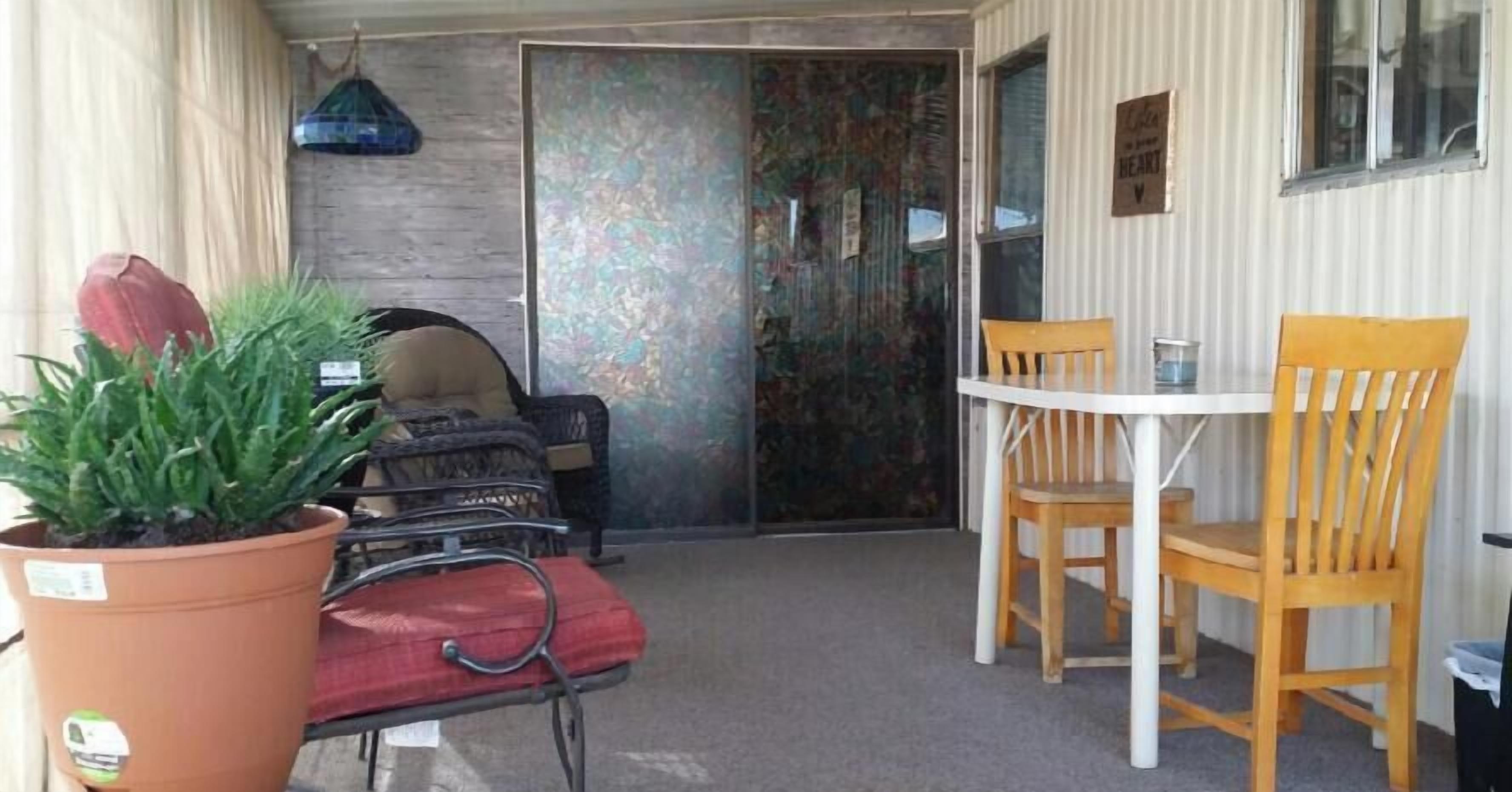 A small room with a table and two chairs, a potted plant, and a red suitcase.
