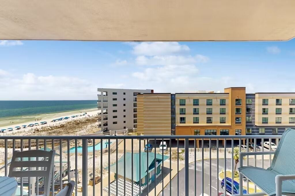 A balcony with a view of a beach and buildings.