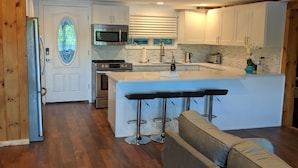 A modern kitchen with wooden paneling, a central island with bar stools, and a built-in microwave.