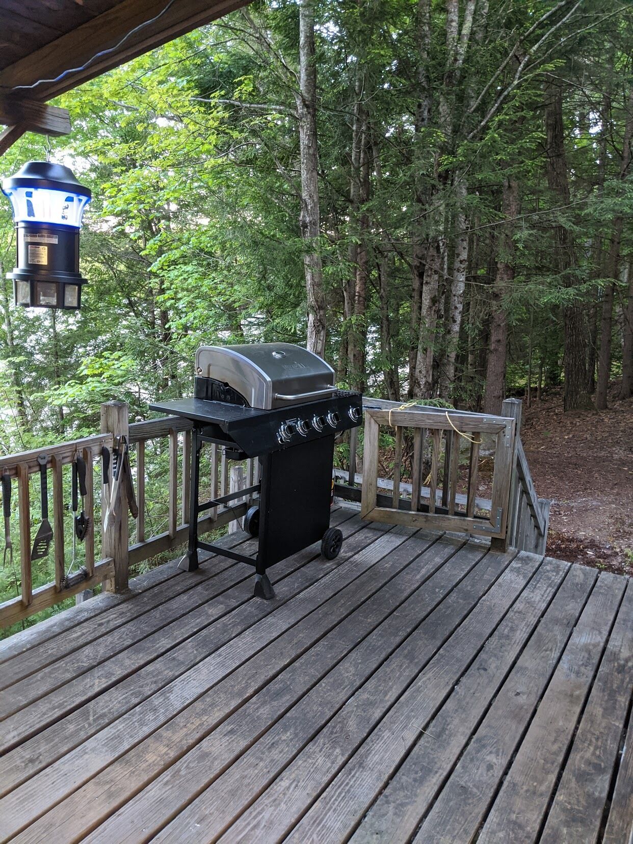 A wooden deck with a grill and a lantern.