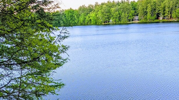 A lakeside patio with a table and chairs, a boat, and a dock.