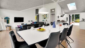 A modern kitchen with white cabinets, a dining area with a white table, and a large window providing natural light.