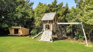 A wooden playhouse with a slide and a separate wooden structure.