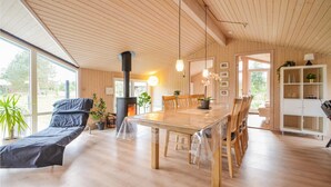 Ein geräumiger Wohnbereich mit Holzboden, einem großen Esstisch und einem eingebauten Kamin. Mehrere Stühle stehen um den Tisch, und ein Sofa befindet sich in der Nähe des Kamins.