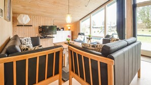 Ein modernes Wohnzimmer mit Holzboden, einem Fernseher, einem Esstisch und einer Couch.