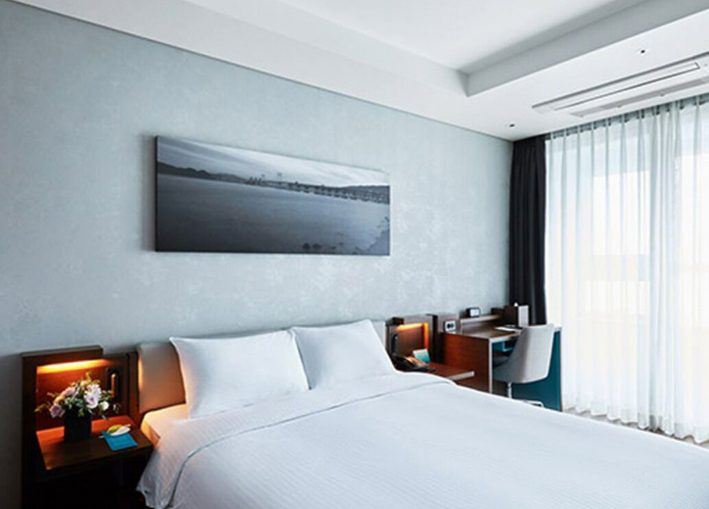 Ein modernes Hotelzimmer mit einem großen Bett, einem Schreibtisch und einem Stuhl.