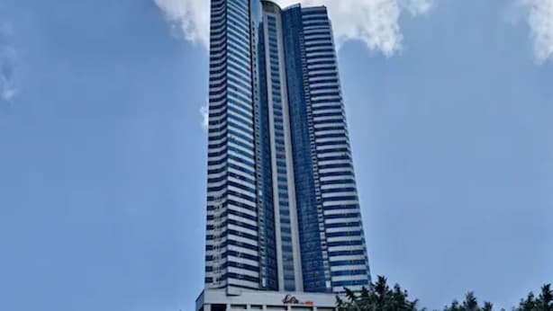 Un gratte-ciel moderne et imposant, doté d’une architecture originale aux lignes courbes, comprenant de nombreux étages et une entrée remarquable à sa base.
