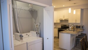 Una cucina compatta con forno integrato, microonde e un piccolo isolotto con sgabelli.