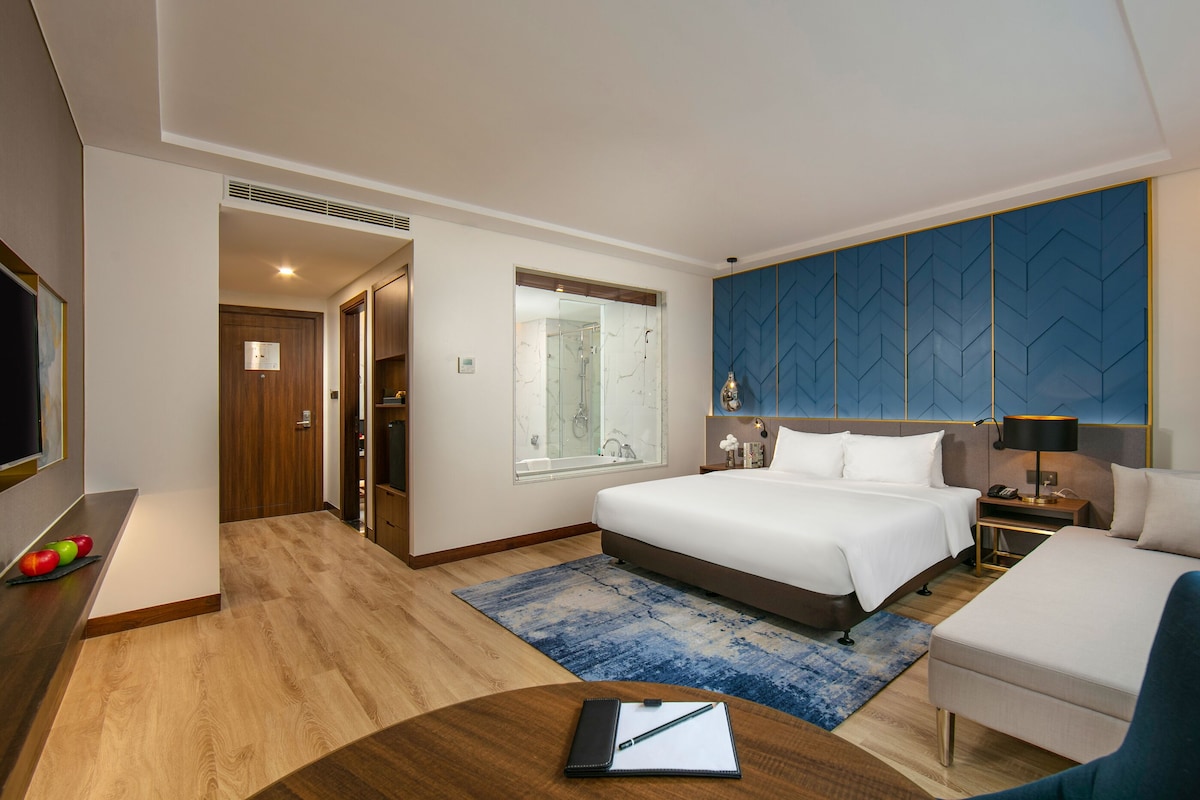 Une chambre d’hôtel équipée d’un lit, d’une table de chevet, d’une chaise et d’un bureau avec un ordinateur.