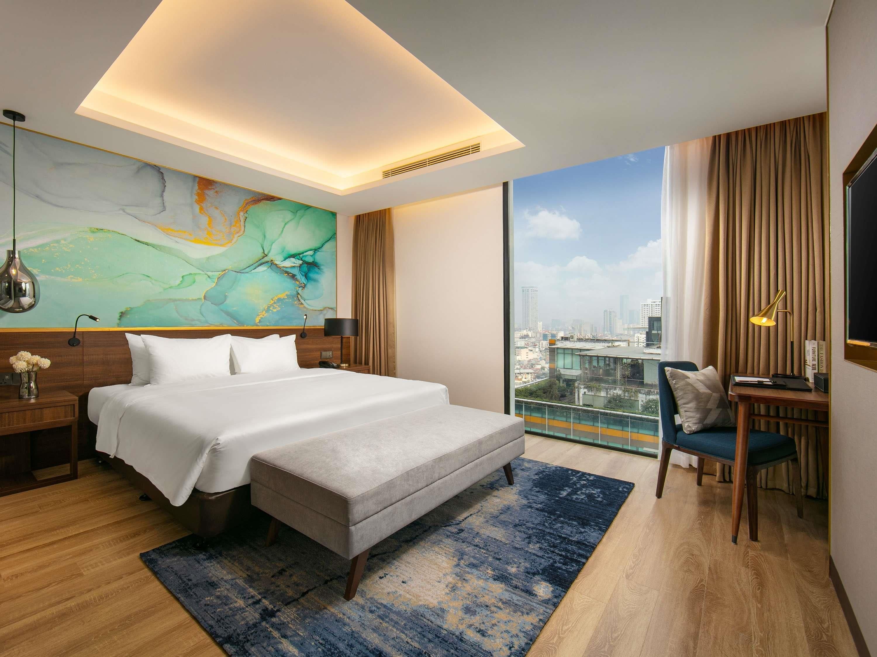 Une chambre d’hôtel moderne avec un grand lit, un bureau et une vue sur la ville.