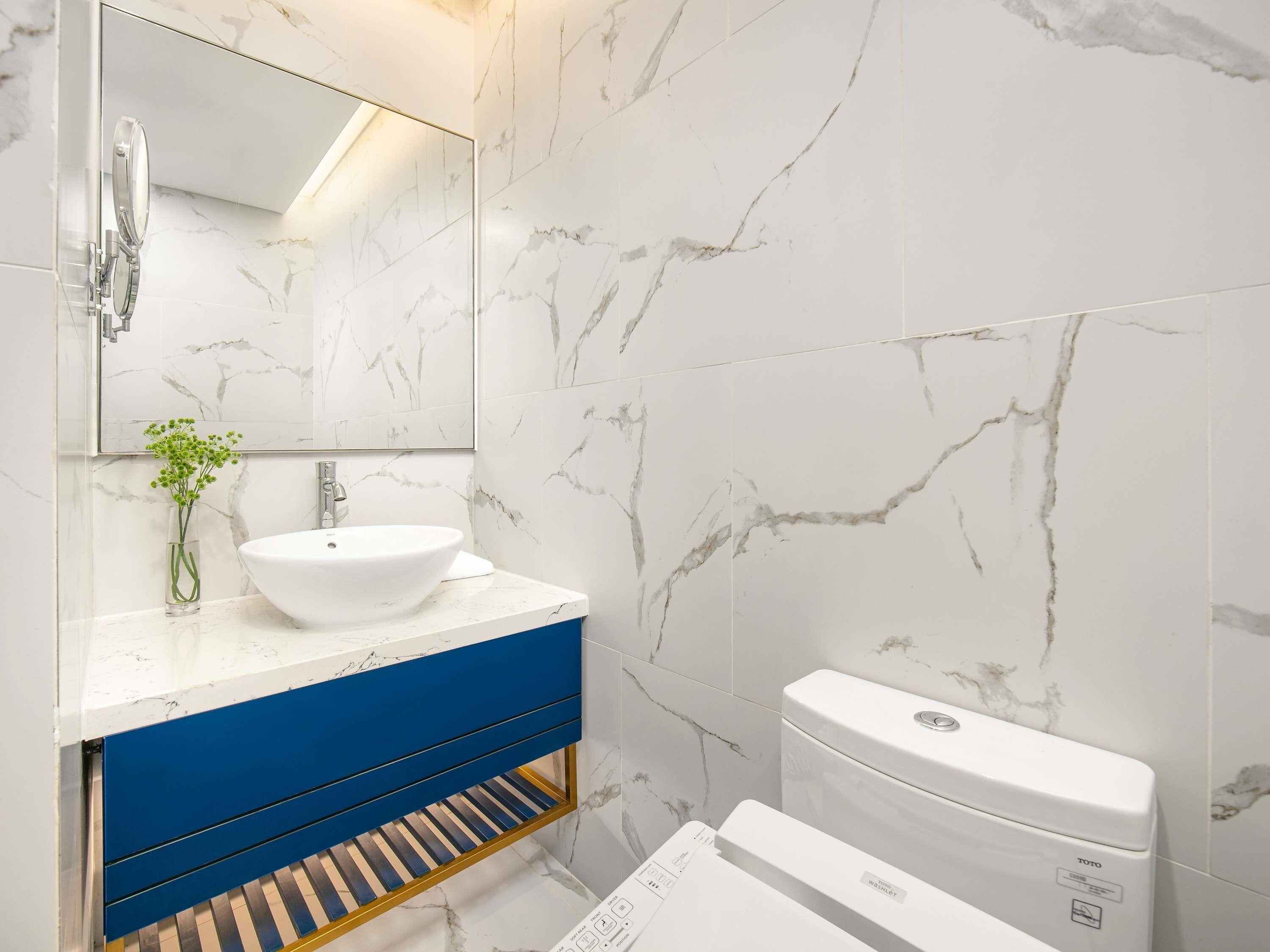 A bathroom with a white sink, blue vanity, and a toilet.