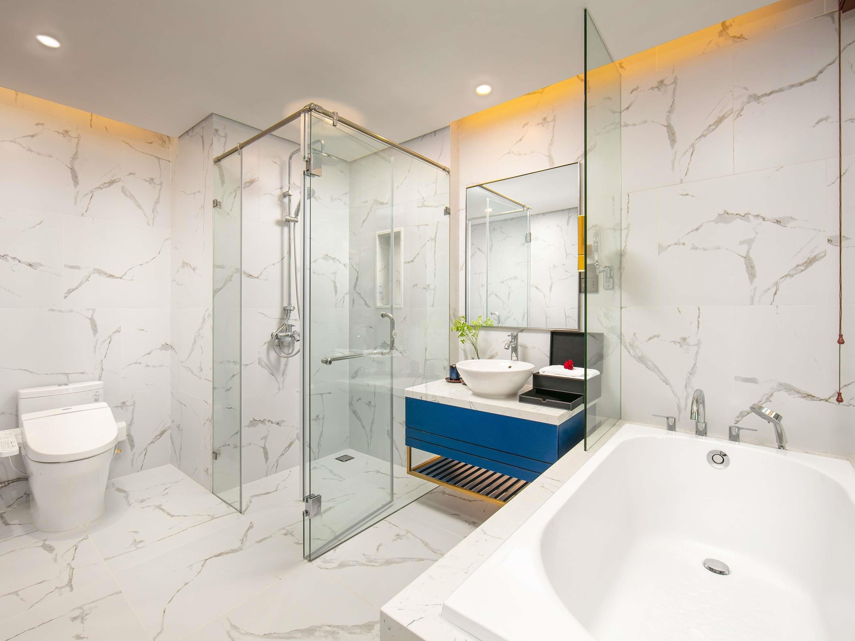 Une salle de bain moderne avec une douche à parois de verre, une baignoire blanche et un meuble-lavabo avec un meuble bleu.