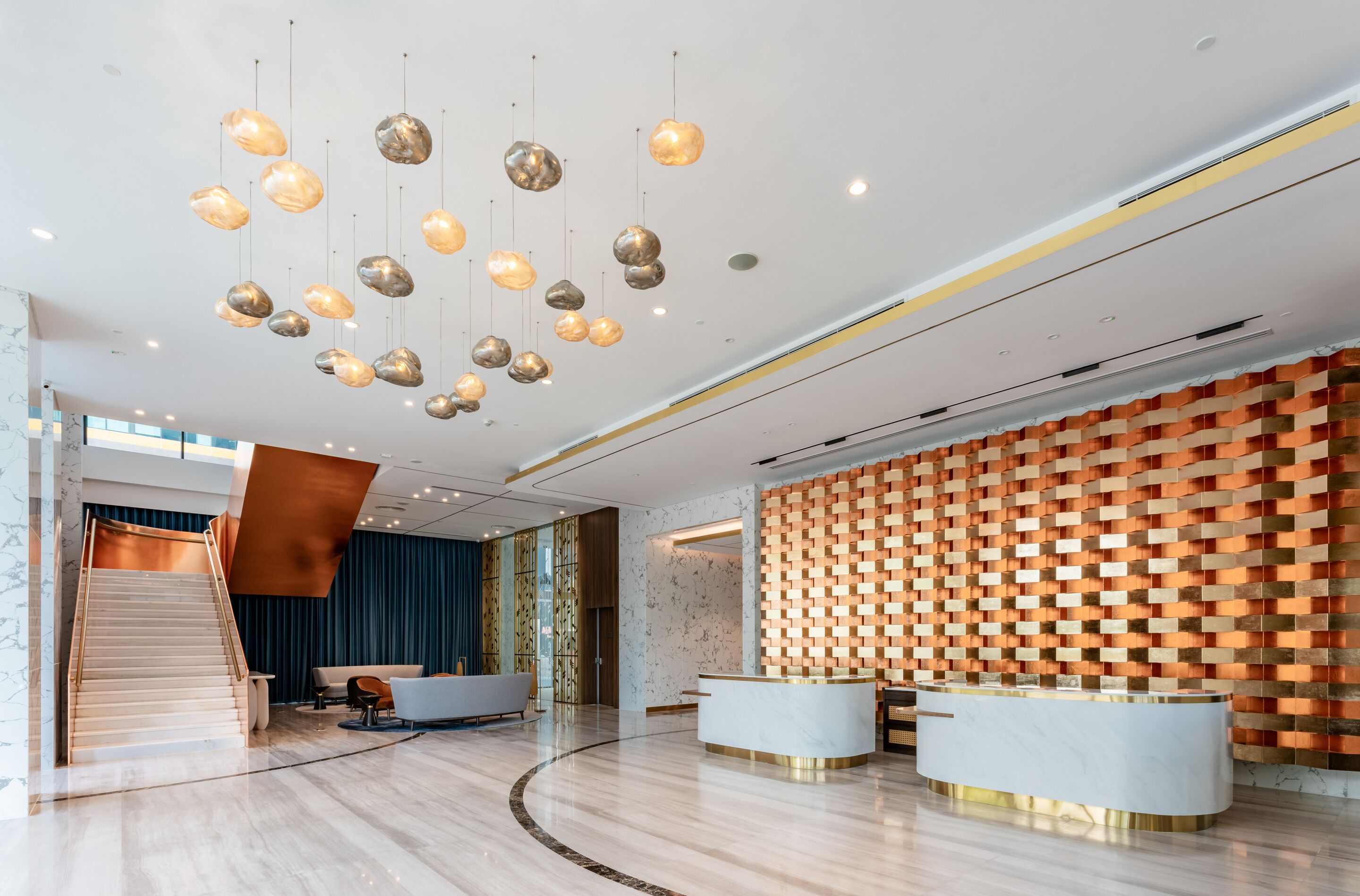 A modern reception area with a marble reception desk, a staircase, and a unique patterned wall.