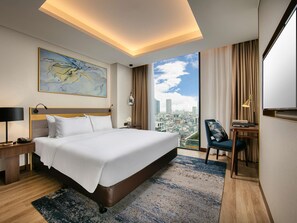 Una habitación de hotel con una cama grande, un escritorio, una silla, vistas a la ciudad y un mapa en la pared.