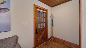 Une porte en bois avec une fenêtre, un porte-manteau et un tableau accroché au mur.