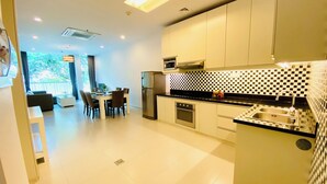 Uma cozinha moderna com painel de fundo xadrez preto e branco, eletrodomésticos de aço inoxidável e um espaço de jantar com vista para o verde.