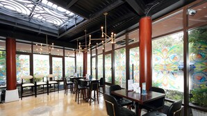 A spacious restaurant with high ceilings, large windows with colorful stained glass, and modern lighting fixtures. - Glenwood Residences (Ho Chi Minh City)