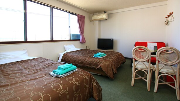 A hotel room with two beds, a television, a desk with a chair, and a window with curtains. - Hotel New Nishida (Tokunoshima)