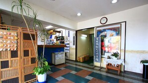 A reception area with a check-in counter, a clock, and a wall-mounted sign. - Hotel New Nishida (Tokunoshima)