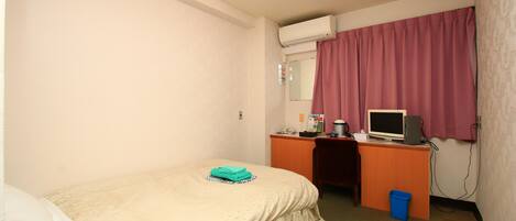 Una habitación de hotel con una cama, un escritorio con computadora, televisión y ventana con cortinas.