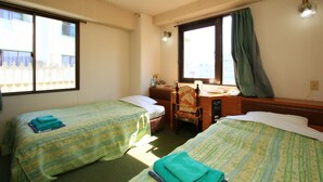 A hotel room with two beds, a desk, a chair, and a window with curtains. - Hotel New Nishida (Tokunoshima)