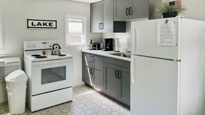 Une cuisine équipée d’une cuisinière, d’un four, d’un réfrigérateur et de meubles de rangement gris.