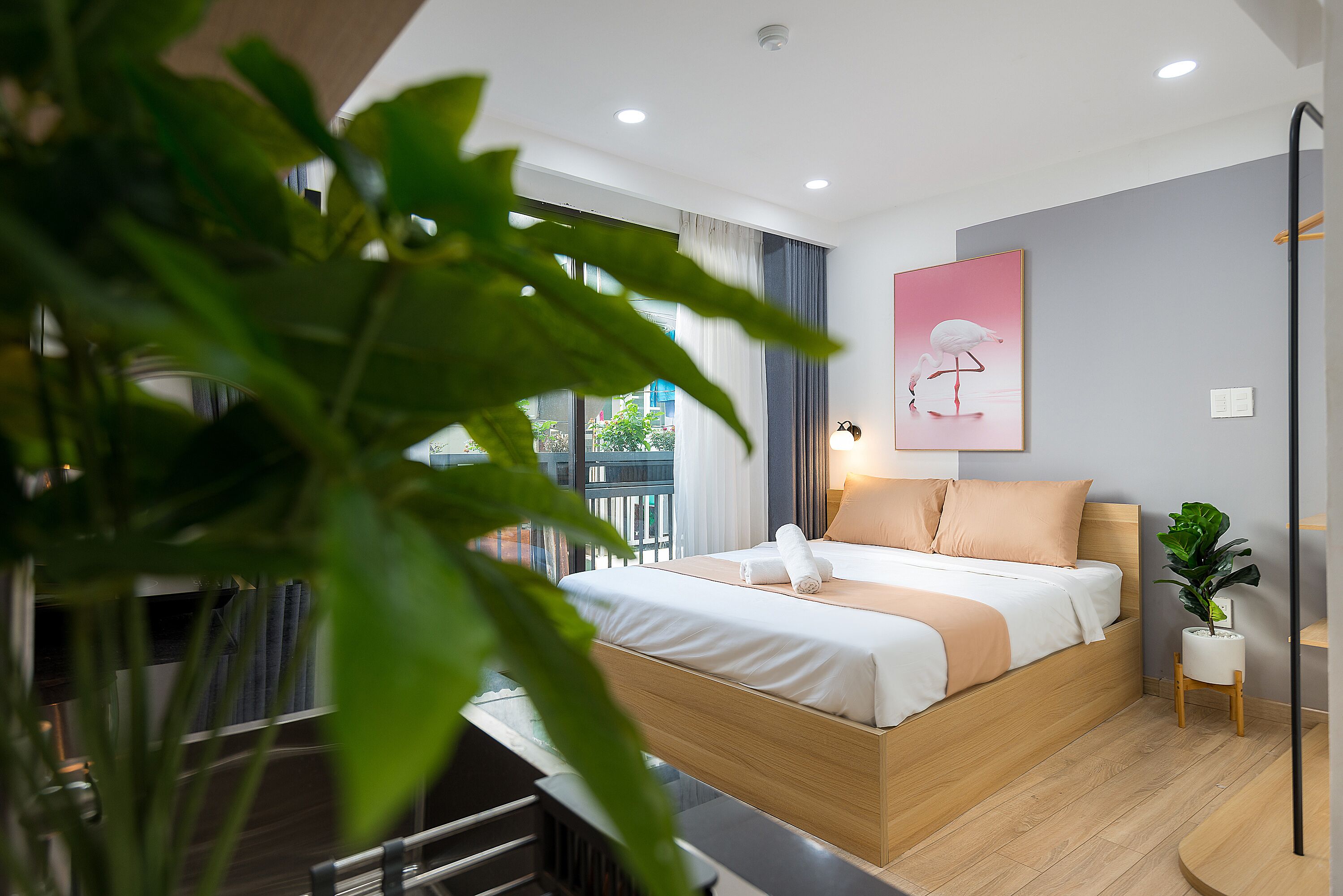 Een moderne hotelkamer met een houten bed, een groot raam en een potplant.