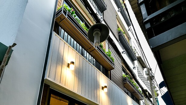 Ein modernes Gebäude mit mehreren Balkonen, großen Fenstern und einem sichtbaren Innenraum mit einer Treppe.