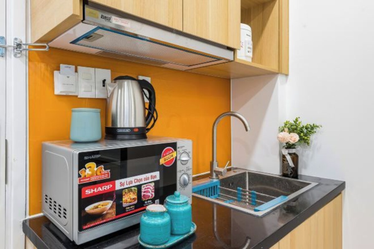 A compact kitchen with a microwave, kettle, and sink.