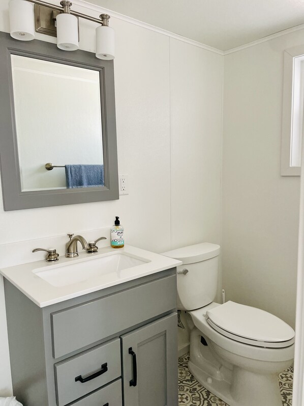 Un baño con un lavamanos blanco, un espejo, un inodoro y un mueble con cajones.