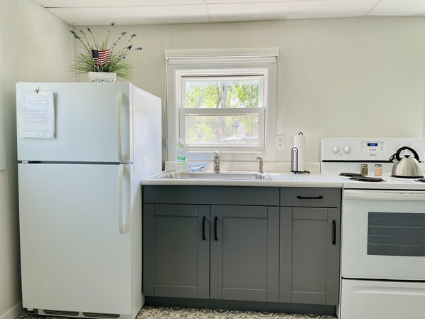 A kitchen with a refrigerator, sink, stove, and cabinets. - West Lake Okoboji Cub Cottage (Arnolds Park)