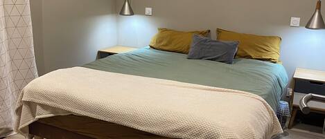 A bedroom with a bed, bedside tables, a nightstand, a floor lamp, and a rug.