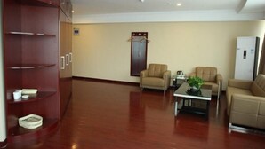 A spacious room with a wooden cabinet, two beige armchairs, a coffee table, and a refrigerator. - Greentree Inn Linyi Yitang Town Shuangling Road Ex (Linyi)