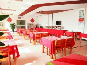 Uma sala de jantar com mesas, cadeiras, uma televisão e uma planta.