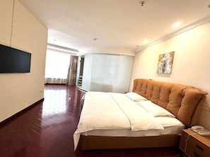 Una habitación de hotel moderna con una cama grande, un televisor de pantalla plana montado en la pared y un cuadro sobre la cama.