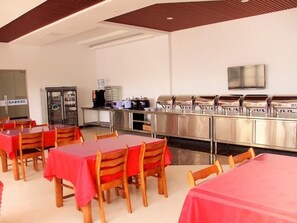 Een eetgedeelte met tafels, stoelen, een buffet en een koelkast.