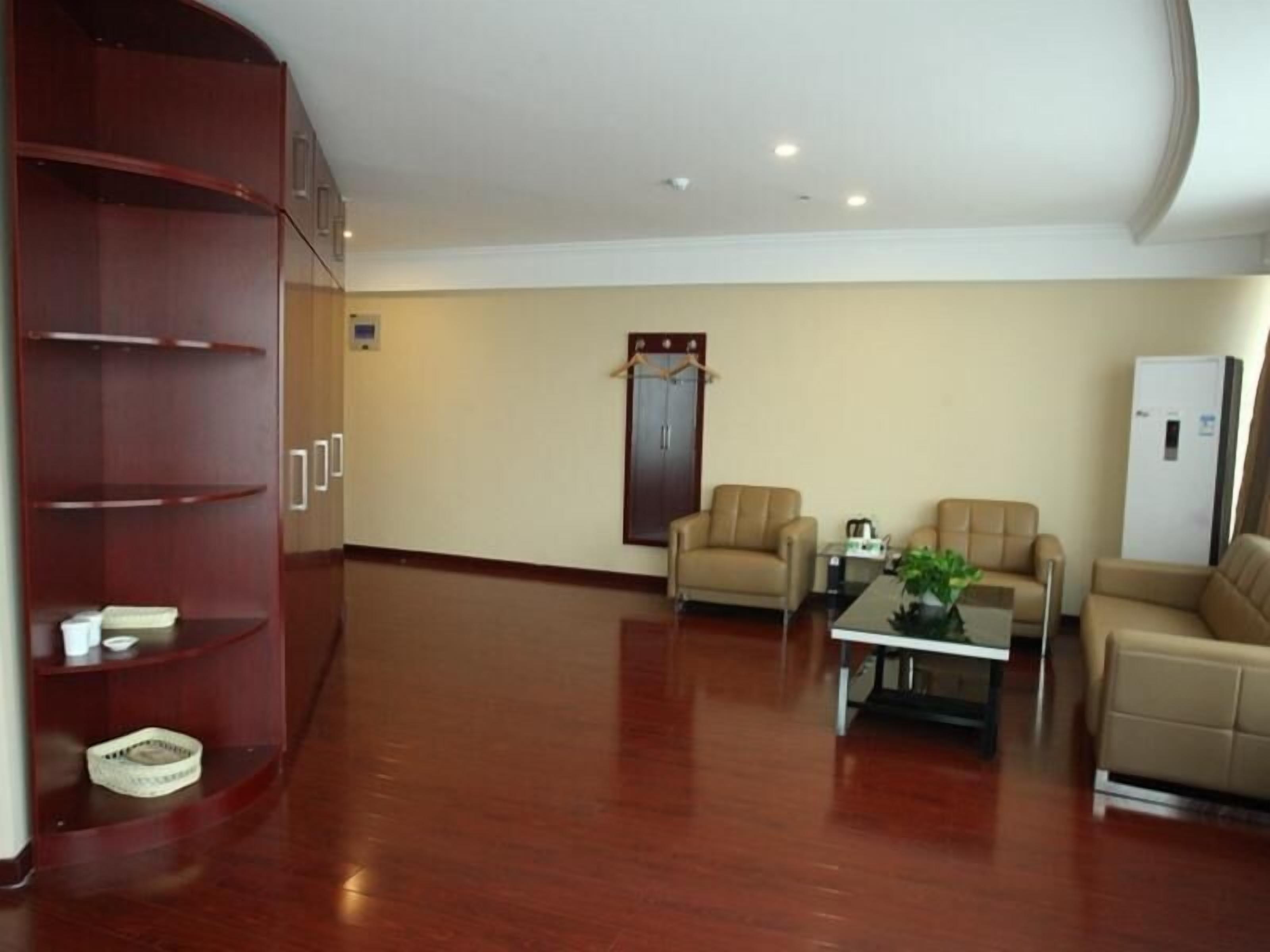 A spacious room with a wooden cabinet, two beige sofas, a coffee table, and a refrigerator.