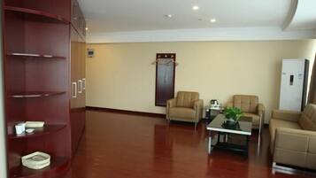 A spacious room with a wooden cabinet, two beige sofas, a coffee table, and a refrigerator.